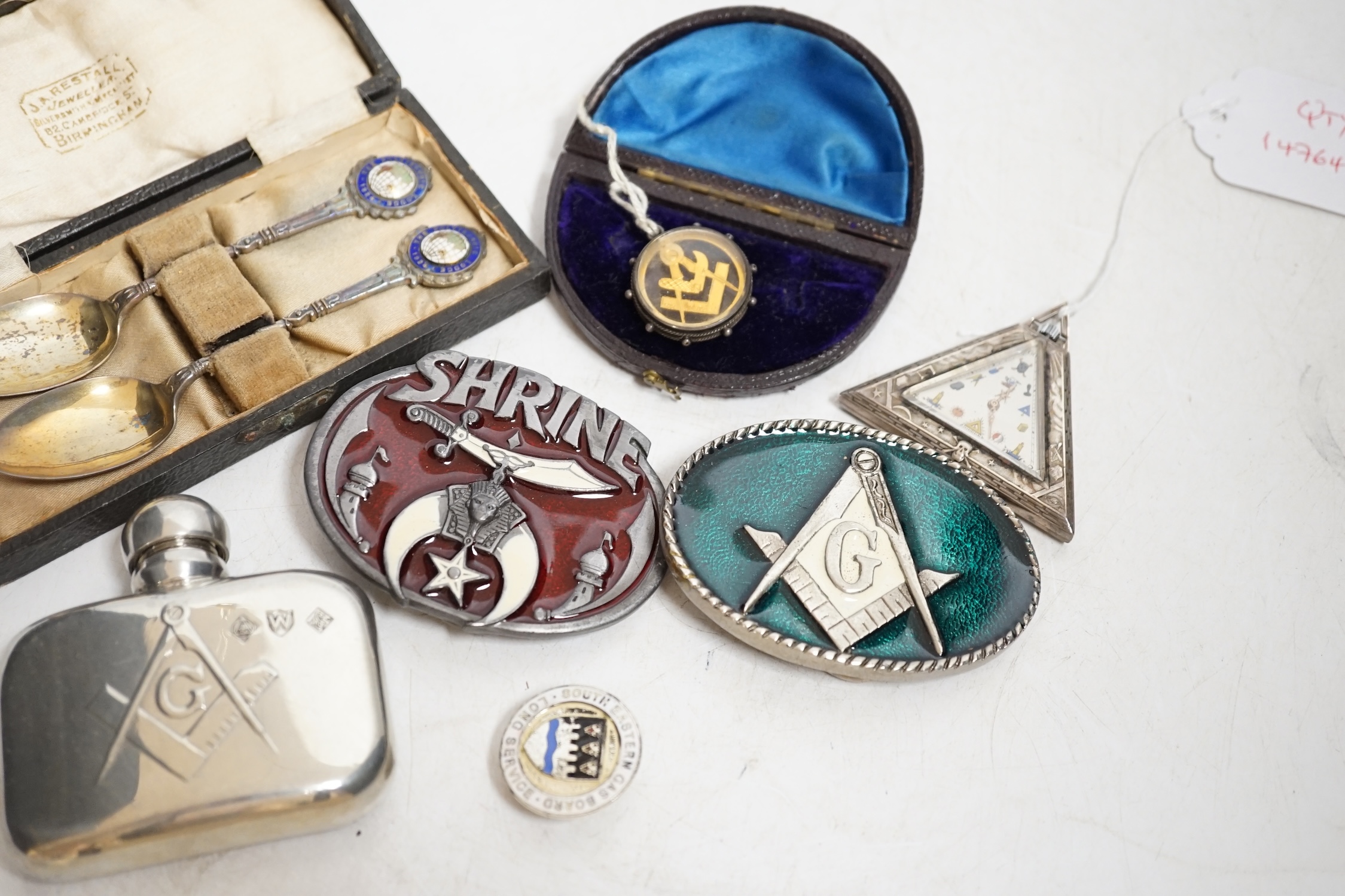 A collection of objects to include a triangular Masonic silver pocket watch, assorted Masonic fobs, enamel buckles, silver presentation spoons and sundries. Condition - varies, mostly fair
